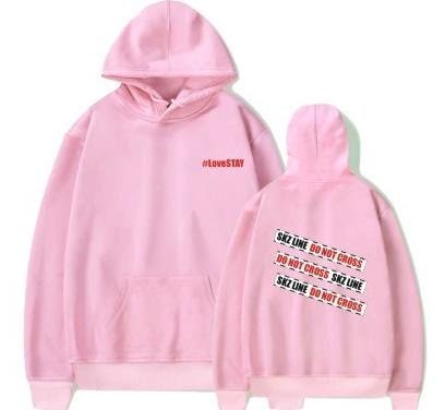 Soft pink oversized hoodie with "#LoveSTAY" text on the front and "SKZ LINE DO NOT CROSS" graphic on the back, perfect for K-pop fans.