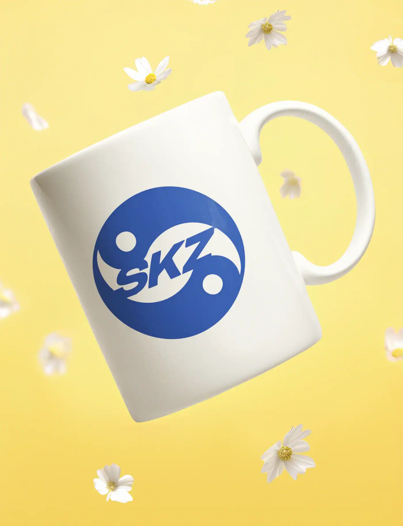 Skz logo on a white mug surrounded by small white flowers on a yellow background.